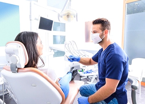 Female patient sitting in dental chair talking to male dentist