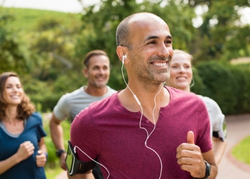 Man with dental implant replacement tooth smiling and jogging with friends