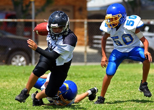 Young athletes playing football with athletic mouthguards