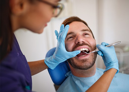 Dental team member examining patient's smile during tooth preparation