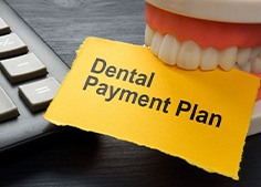 Tooth model holding paper that says “dental payment plan”