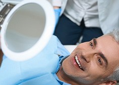 A man admiring his new dental implants in a mirror