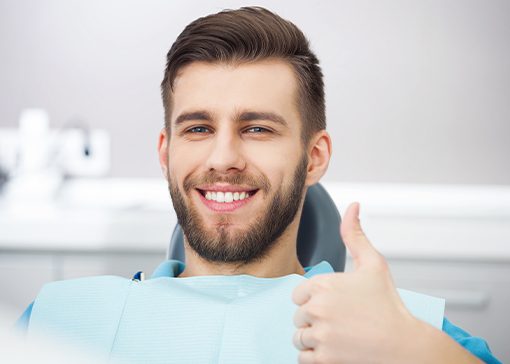 Man in dental chair smiling after one visit dental restoration