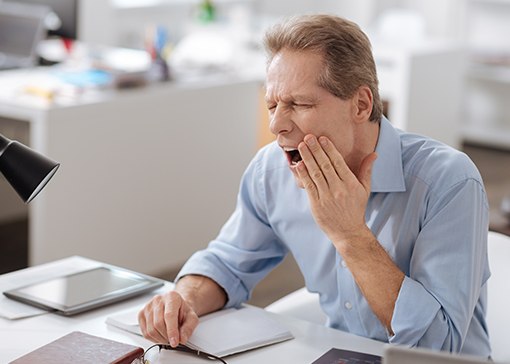 Man in need of nightguard for bruxism holding jaw in pain