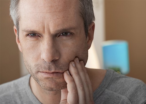 Man in need of emergency dentistry holding cheek