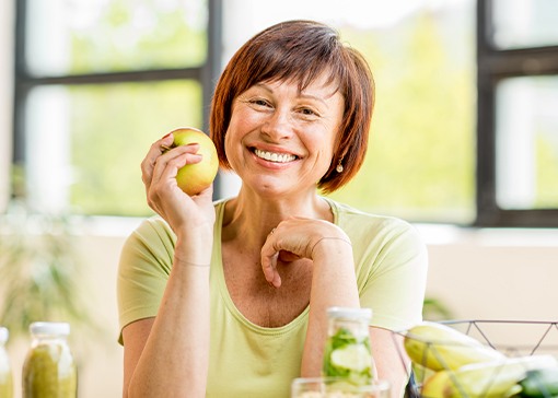 Smiling woman with a fixed bridge holding an apple