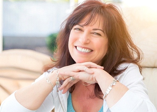 Woman with brown hair smiling with chin resting on hands