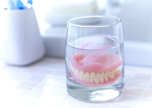 Full dentures in North Andover soaking in glass