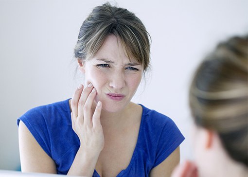Woman in pain before emergency dentistry holding cheek
