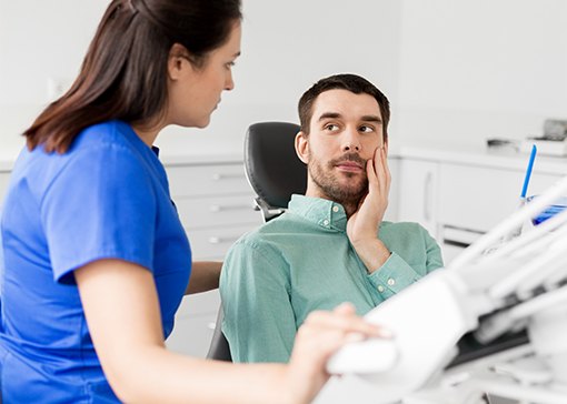 Man in need of emergency dentistry holding cheek