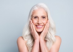 Woman with white hair holding hands to her cheeks 
