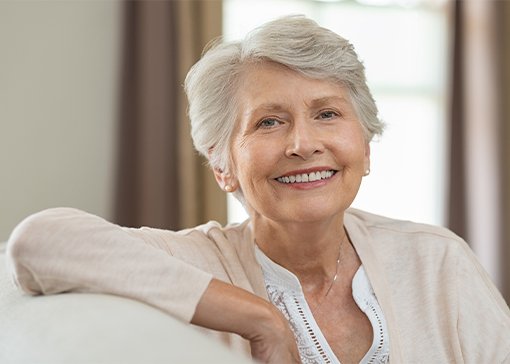 Woman with gorgeous smile after dental implant supported denture tooth replacement