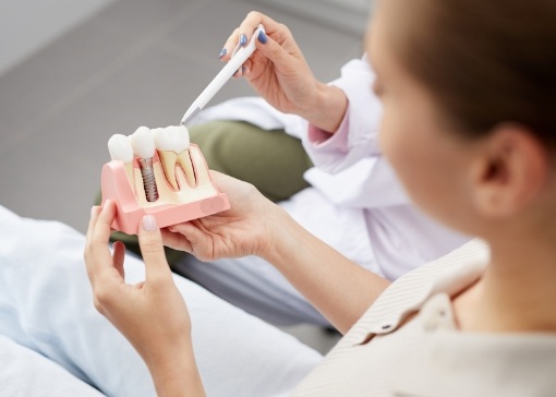 Dentist and patient looking at dental implant tooth replacement model