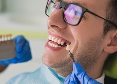 Man with missing tooth having smile compared with dental restoration shade options