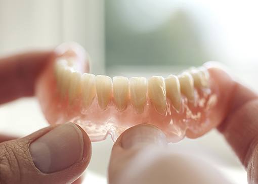 Hand holding a full denture