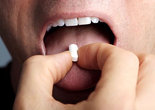 Man placing sedative pill on his tongue