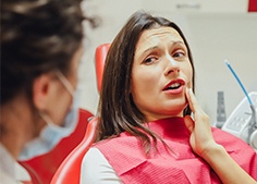 Woman holding cheek during gum disease treatment visit