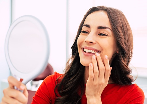 Woman looking in mirror after smile makeover