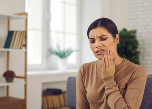 a woman sitting down and rubbing her jaw