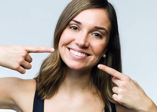 Woman pointing to smile after teeth whitening treatment
