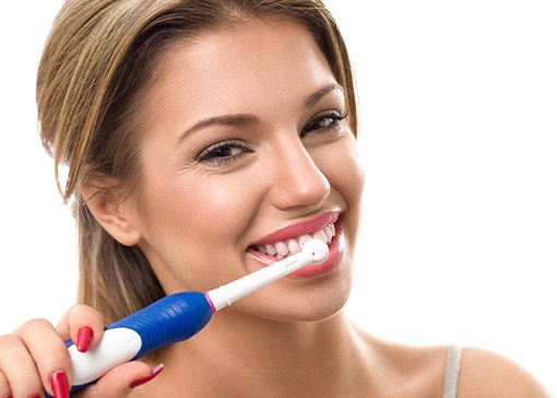 Woman brushing teeth to maintain teeth whitening results