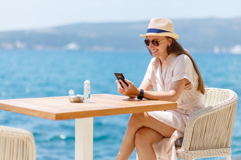 woman texting and smiling during summer vacation