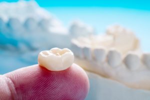 a person holding a dental crown on their fingertip