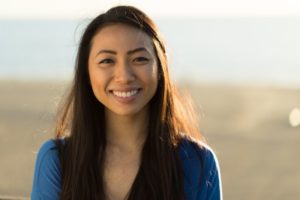 a woman smiling brightly on the beach after getting professional teeth whitening